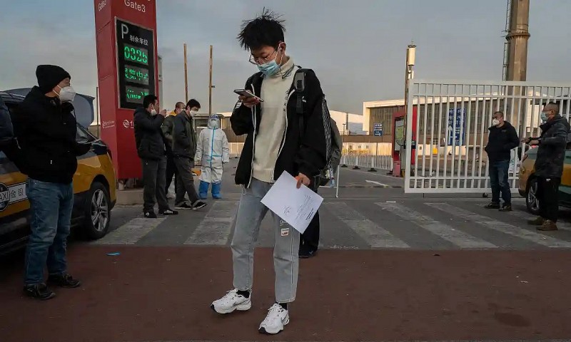 Người đàn ông mang theo giấy tờ sau khi rời khỏi cơ sở cách ly của chính phủ ở Bắc Kinh, Trung Quốc, ngày 7 /12/2022. Ảnh: Kevin Frayer/Getty Images/https://suckhoeviet.org.vn