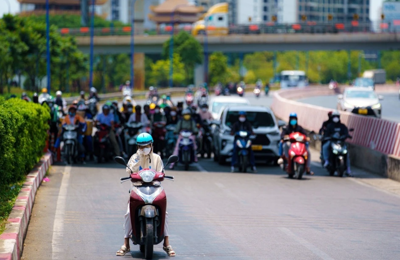 Nhiều người tìm mình nơi có bóng mát trong lúc dừng chờ đèn đỏ trên xa lộ Hà Nội (TP Thủ Đức). Ảnh: Chí Hùng.